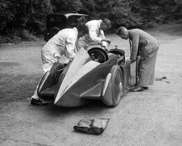 Mechanics working on Leon Cushman's Austin 7 racer for a speed record attempt, Brooklands, 1931. Artist: Bill Brunell.