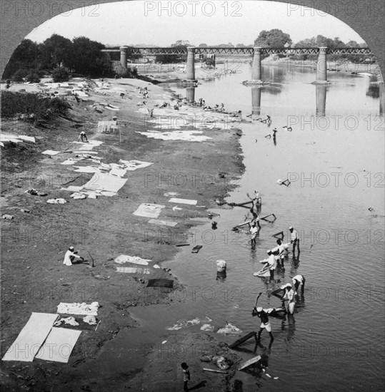 Dbobies washing clothes in the Goomti River, near Lucknow, India, 1900s.Artist: Underwood & Underwood