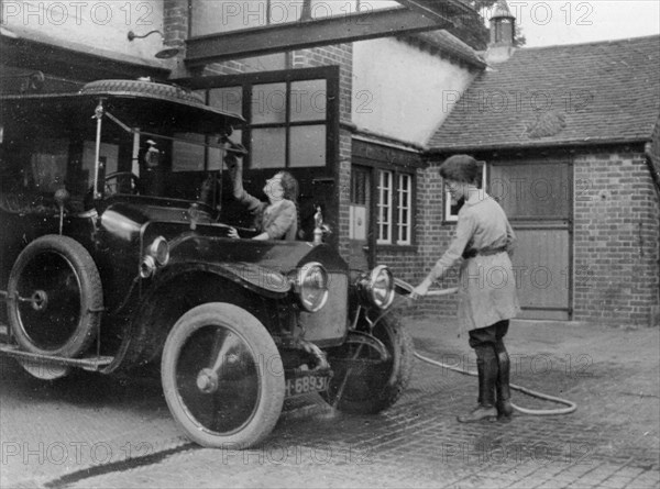 Chauffeuse washing car with hosepipe circa 1911. Creator: Unknown.