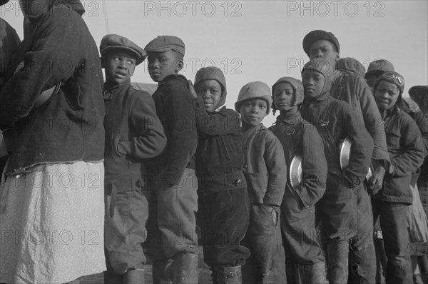 Possibly: Negroes in the lineup for food at the flood refugee camp, Forrest City, Arkansas, 1937. Creator: Walker Evans.