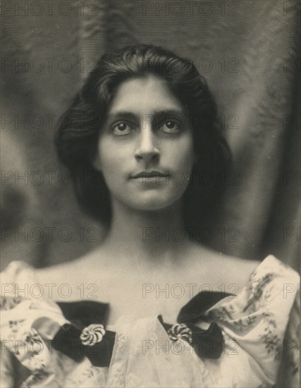 Portrait of a woman in a floral dress adorned with diamond brooches and bows, c1900.