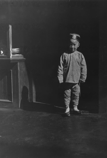 Boy in doorway of lamp store, Chinatown, San Francisco, between 1896 and 1906. Creator: Arnold Genthe.