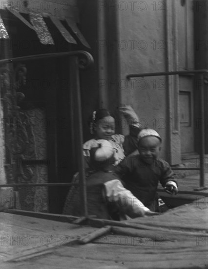 Three children in front of a cellar door, Chinatown, San Francisco, between 1896 and 1906. Creator: Arnold Genthe.