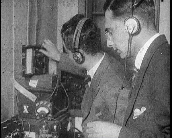 Two Men Wearing Headphones and Calibrating Wireless Equipment, 1922. Creator: British Pathe Ltd.