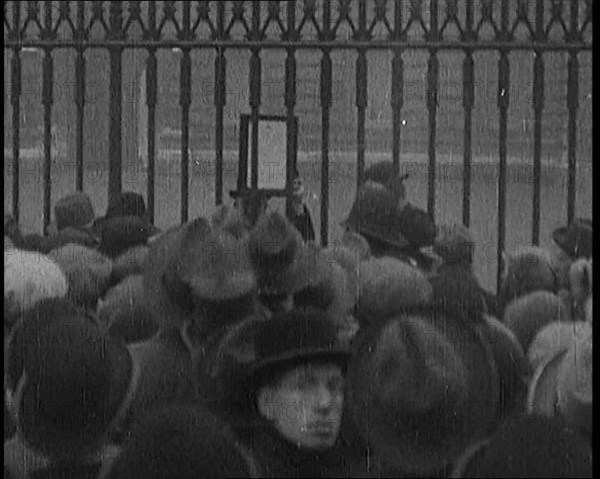 A Male Civilian Holding up a Bulletin from the Doctor to Crowds Gathering Outside..., 1929. Creator: British Pathe Ltd.