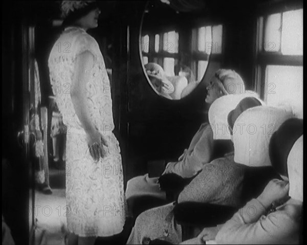 Female Civilian Wearing a Dress and Hat Modelling in Front of a Small Audience Inside a..., 1920. Creator: British Pathe Ltd.