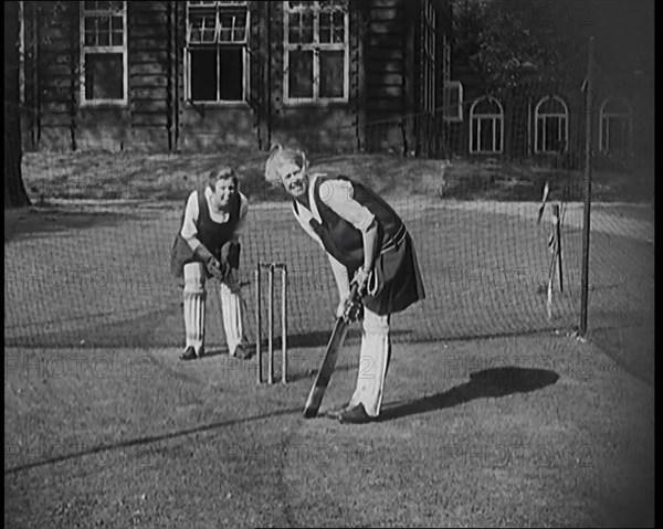 Two Female Civilians Wearing Gymslips and Batting Pads Preparing to Bat in a Playing Field, 1920. Creator: British Pathe Ltd.