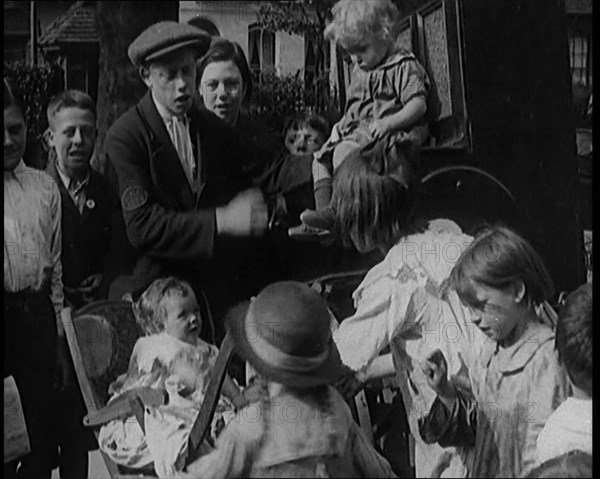 A Group of Civilian Children Dancing in Front of a Hurdy Gurdy Watched by a Small Crowd..., 1920. Creator: British Pathe Ltd.