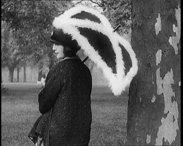 Female Civilian Dressed Glamorously Holding a Fur Trimmed Parasol in a Park, 1920. Creator: British Pathe Ltd.