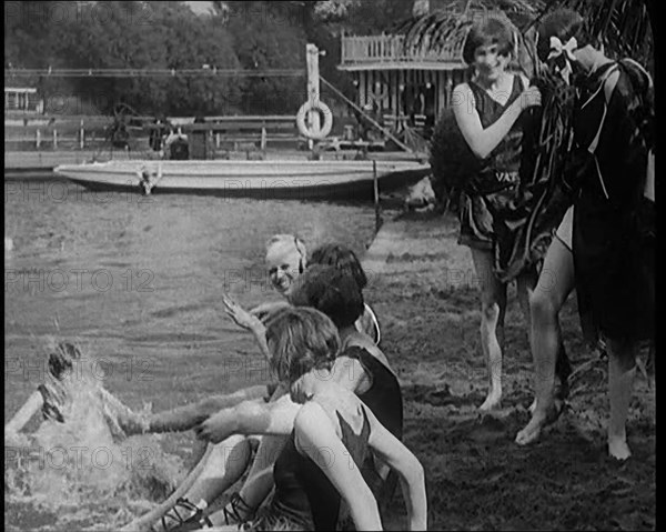 A Group of Young Female Civilians Wearing Swimsuits Playing on Riverside, 1920. Creator: British Pathe Ltd.