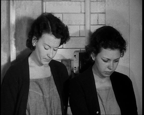 American Female Civilians Wearing Prisoners Outfits Standing Against a Wall in a Prison, 1930. Creator: British Pathe Ltd.