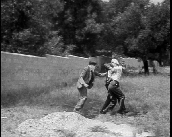 Two Male American Civilians Covering Their Faces with Handkerchiefs Carrying a Male American...1930. Creator: British Pathe Ltd.