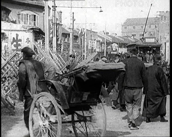 A Male Chinese Civilian Pulling Rickshaws Through the Streets of Shanghai Past Barricades, 1920s. Creator: British Pathe Ltd.