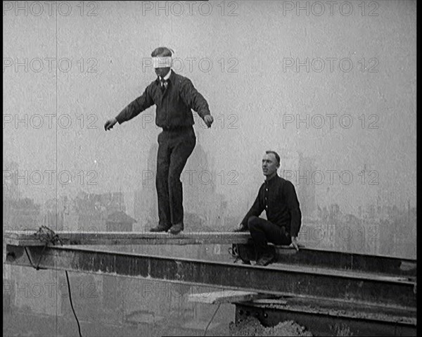 Blindfolded Man Walking Across a Plank Suspended from Iron Girders High Above the City Streets, 1921 Creator: British Pathe Ltd.