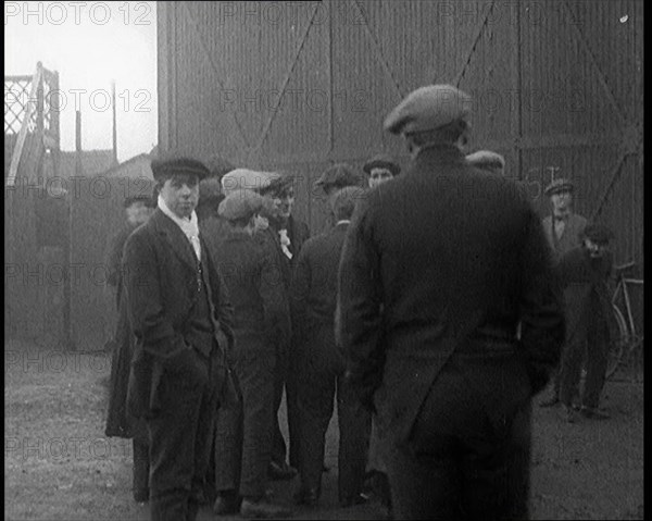 Male Civilian in a Flat Cap Facing a Wall. Another Male Civilian Carries a Sack Over His..., 1924. Creator: British Pathe Ltd.