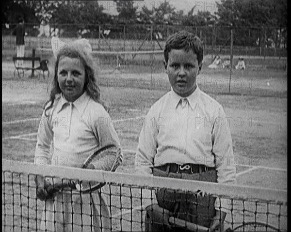 British Tennis Player Betty Nuttall as a Child, Standing on a Tennis Court With a Young Boy, 1921. Creator: British Pathe Ltd.