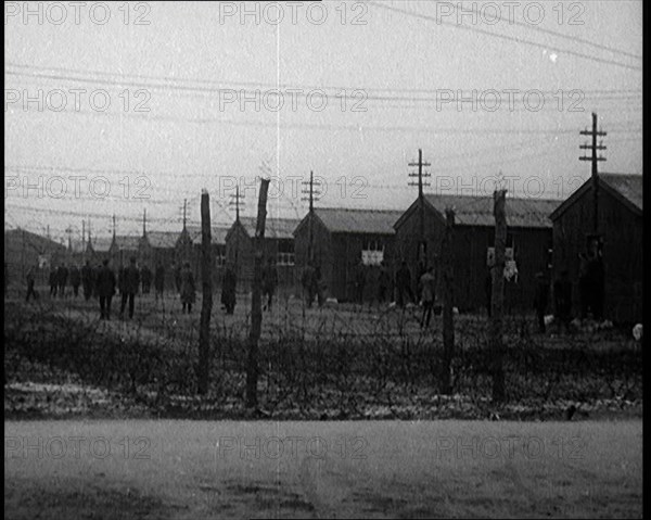 Irish Prisoners Walking Across a Barbed Wire Fenced Prison Ground, 1921. Creator: British Pathe Ltd.