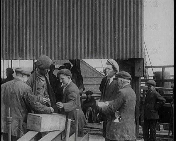 A Group of Miners Gathering and Smoking at a Pit Head, 1920. Creator: British Pathe Ltd.