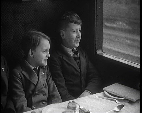 Two Male Children in a Train Carriage Sitting in Front of a Table Laid for a Meal, 1931. Creator: British Pathe Ltd.