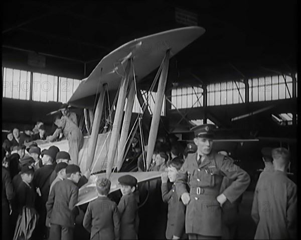 An RAF Officer Showing a Group of Male Children His Aeroplane, 1931. Creator: British Pathe Ltd.