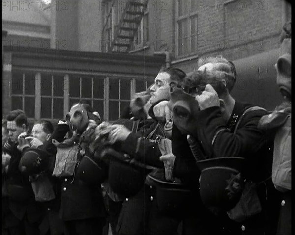 Male Police Civil Defence Volunteers Practice Putting on Gas Masks in a Yard Behind a Brick..., 1938 Creator: British Pathe Ltd.