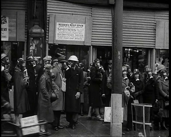 Men and Women Waiting on a Pavement Wearing Gas Masks, 1939. Creator: British Pathe Ltd.