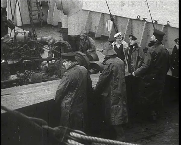 Male Ship's Crew Standing Near Rigging and Machinery on Deck of a Freighter, 1939. Creator: British Pathe Ltd.