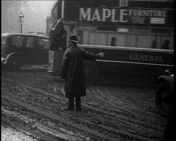 A Male Police Officer Directing the Traffic in the Snow, With His Back to the Camera, 1920s. Creator: British Pathe Ltd.