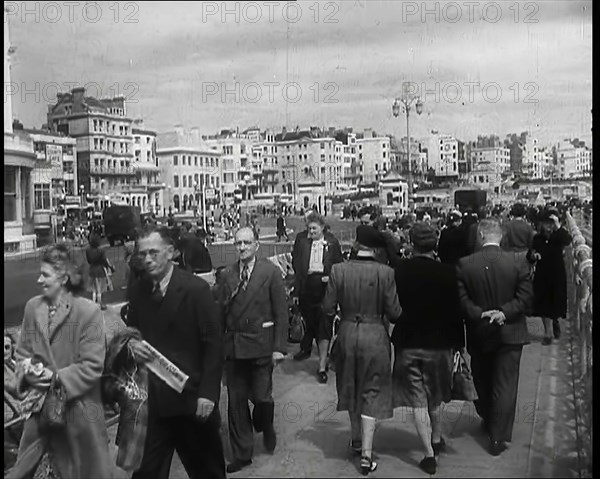 A Cloudy Day as Male and Female Pedestrians are Walking on the Promenade at  Brighton..., 1939. Creator: British Pathe Ltd.