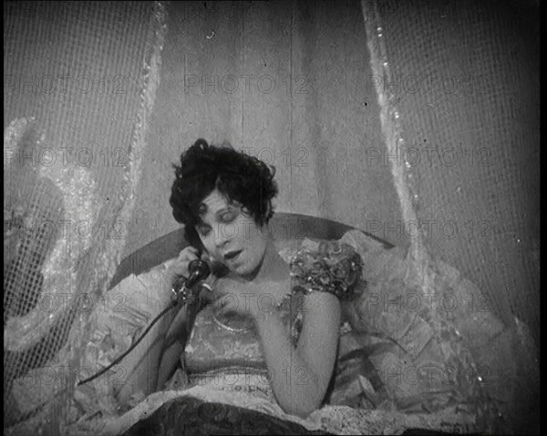 Scene from a 1920s Film. A Female Actor Speaking on the Telephone in Bed Still Wearing Her..., 1920s Creator: British Pathe Ltd.