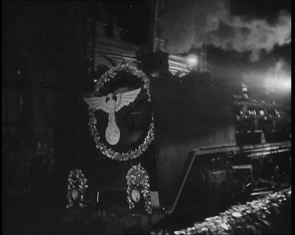 A Steam Train Decorated With Nazi Insignia on the Front Pulls Into a Station at Night, 1937. Creator: British Pathe Ltd.