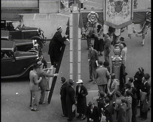 Bud Flanagan With a Frying Pan Climbing a Ladder Resting Against Coronation Decorations in..., 1937. Creator: British Pathe Ltd.