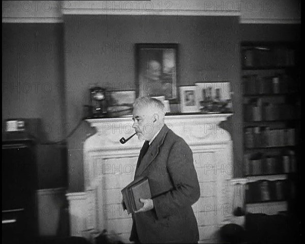 C.E.M Joad Taking Some Books to His Desk, 1930s. Creator: British Pathe Ltd.