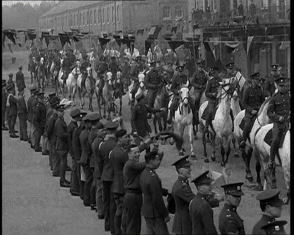 Military Parade of Mounted British Soldiers Riding Down a Street Decorated With Bunting, 1937. Creator: British Pathe Ltd.