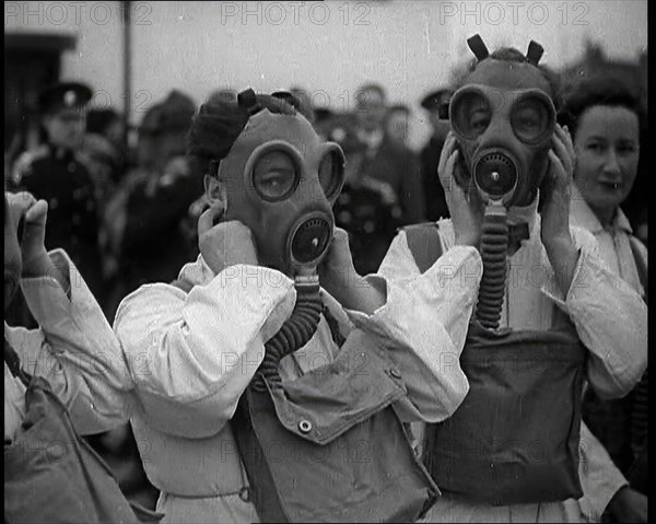 A Close up of Three Female Civil Defence Volunteers in White Boiler Suits Putting on Gas..., 1938. Creator: British Pathe Ltd.