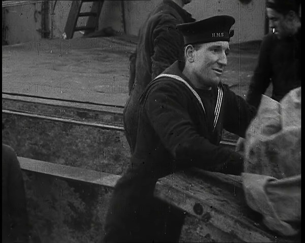 Several Male Crew, Including One from the Royal Navy, Inspecting the Cargo of a Large Vessel, 1939. Creator: British Pathe Ltd.