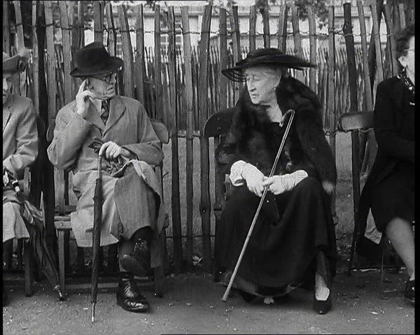 An Elderly Woman Wearing a Wide Hat, a Fur Stole, and Holding a Walking Stick Sitting on a..., 1938. Creator: British Pathe Ltd.