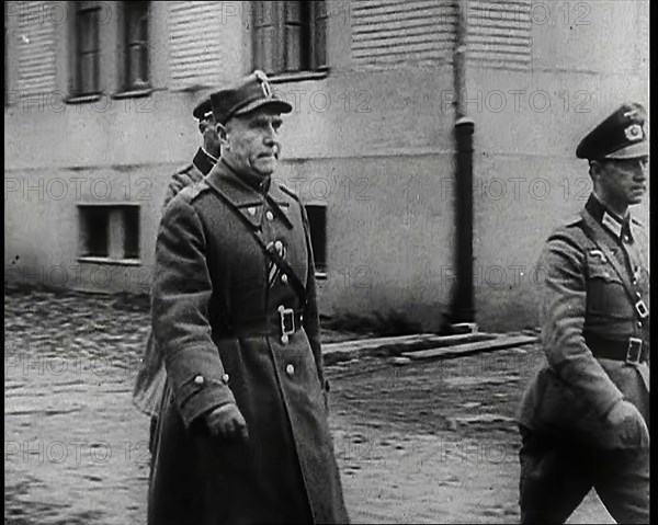 A Male Polish Army Commander Walking Past the Corner of a Large Building With Two Male... 1939. Creator: British Pathe Ltd.