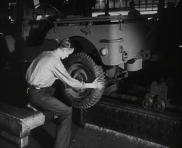 A Worker Fitting Wheels on a Car at an American Factory , 1942. Creator: British Pathe Ltd.