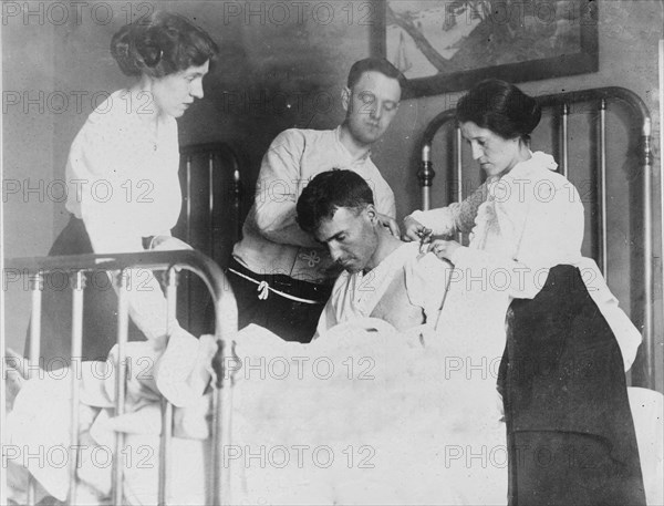 Dr. James F Grant, ship's surgeon, fixing up Gordan G Davidson, survivor of EMPRESS OF..., 1914. Creator: Bain News Service.