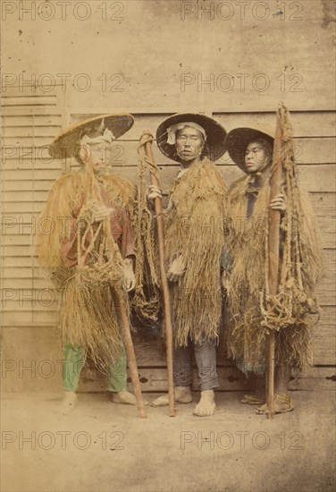 Three Japanese men in grass robes and wide-brimmed hats, 1868-1880. Creator: Felice Beato.