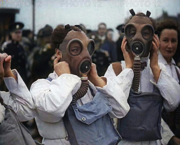 A Close up of Three Female Civil Defence Volunteers in White Boiler Suits Putting on Gas..., 1938. Creator: British Pathe Ltd.