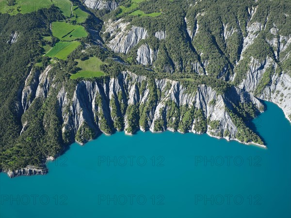 AERIAL VIEW - Landscape of eroded ravines on the lakeshore of Lake Serre-Poncon. La Bréole, Alpes de Haute-Provence, France.