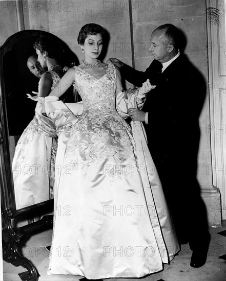 Fashion designer Christian Dior fitting a woman's gown
