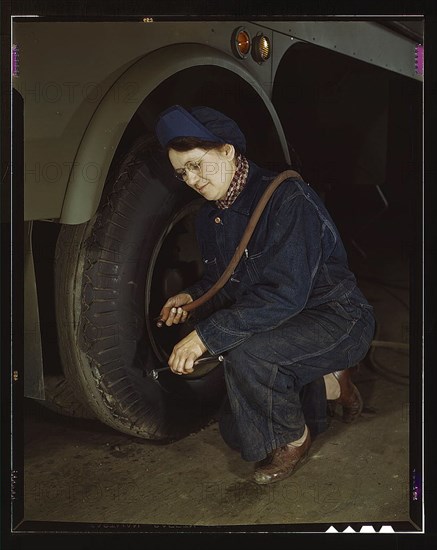 War production workers at the Heil Company making gasoline trailer tanks for the U.S. Army Air Corps., Milwaukee, Wisconsin. Mrs. Angeline Kwint, age 45, an ex-housewife, checking the tires of trailers. Her husband and son are in the U.S. Army (LOC)