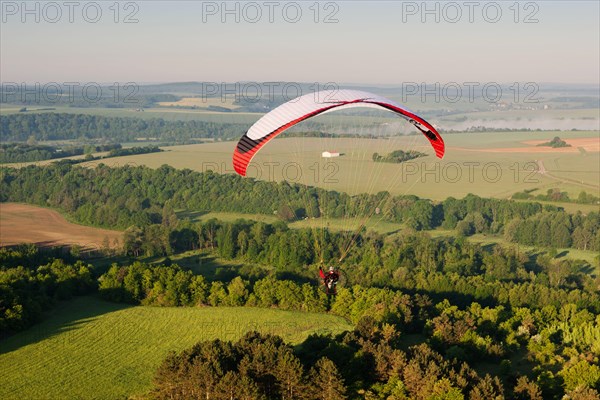 In morning, one paramotor flying over the fields in Yonne department, in Bourgogne-Franche-comté region, France