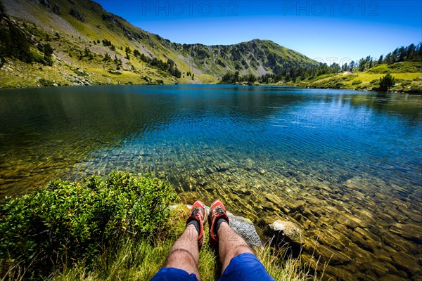 Lake and legs during mountain hiking at Pyrenean mountain