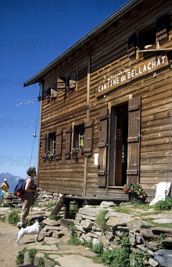 A woman and a dog stand in front of the Refuge de Bellachat, GR 5 Tour du Mont-Blanc from Brévent to Bel Lachat. Chamonix-Mont-Blanc, France, 1990