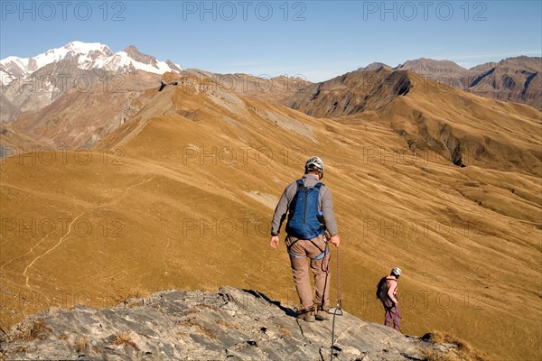 Two people descending a cliff while engaging in the sport of Via Ferrata in the French Alps.