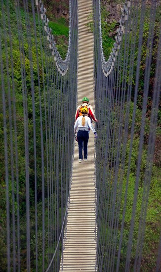 two hikers walking a suspension bridge, France, Mercantour National Park, Lantosque